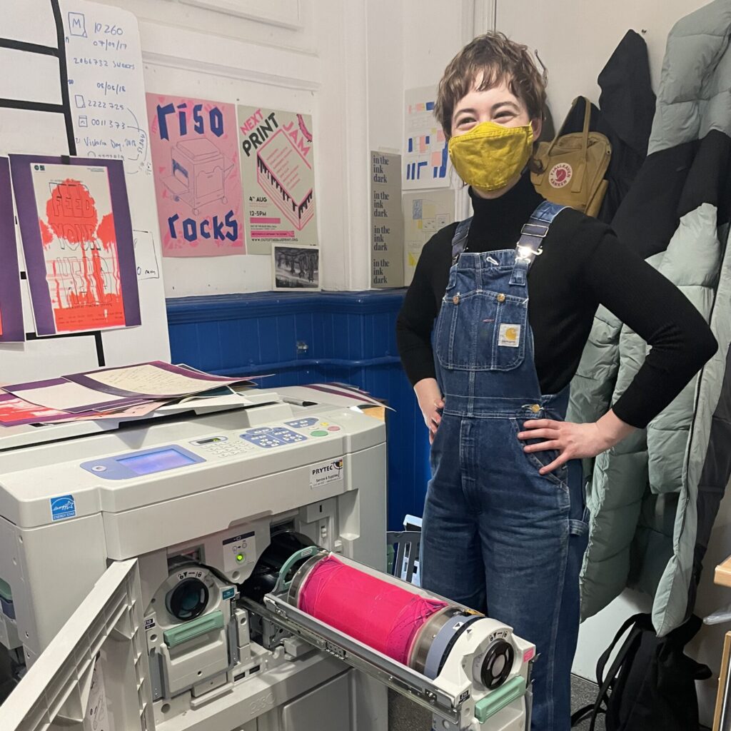 Ot stands next to the riso with the fluorescent pink drum visible